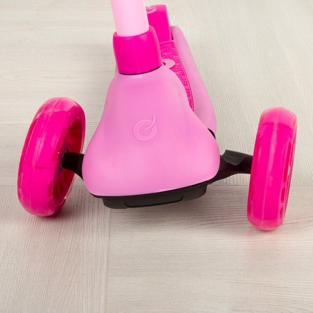 Niño feliz montando patinete 4 en 1 rosa con asiento y manillar de empuje