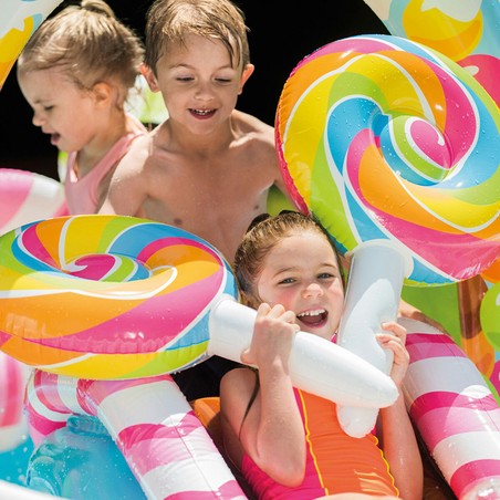 Niños disfrutando de los juegos de agua infantiles en la piscina Intex Candy Zone