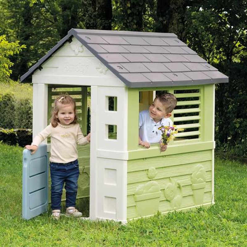 Juego simbólico infantil: Niños explorando la casa de plástico Smoby