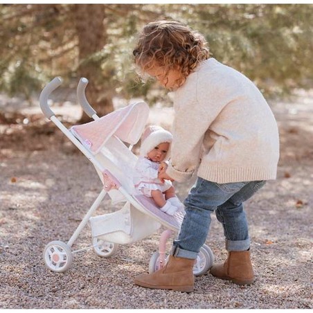 Niña feliz con su cochecito de juguete para muñecas en el parque
